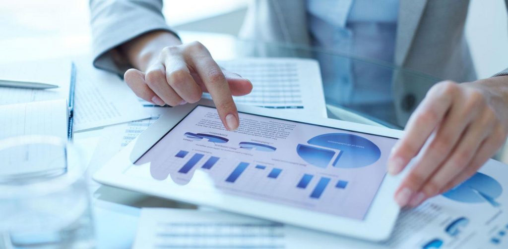 A woman in Hong Kong is pointing at a tablet displaying SEO graphs for digital marketing analysis.