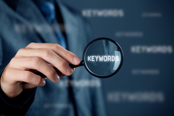 A businessman in Hong Kong holding a magnifying glass over SEO keywords.