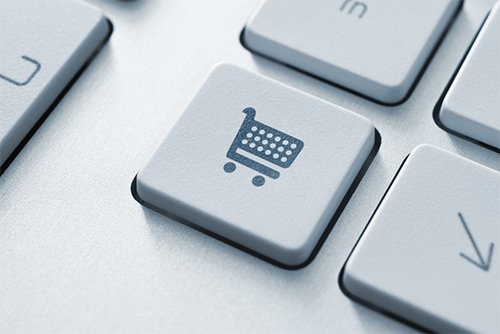 A close up of a shopping cart on a computer keyboard emphasizing e-commerce.