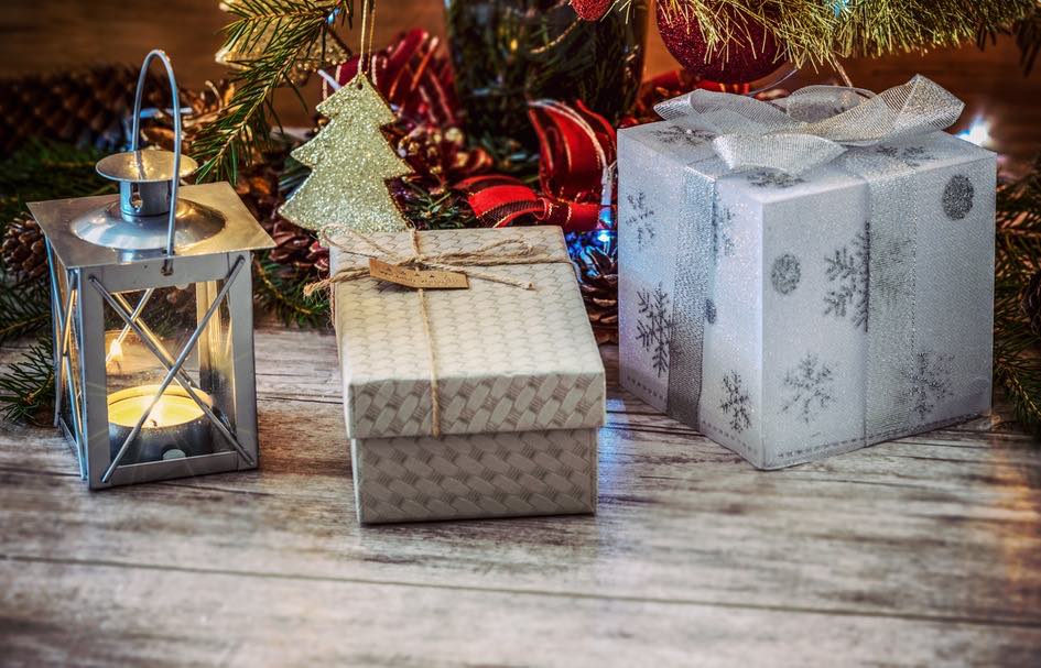 A festive Christmas tree adorned with gifts and a lantern, set against a wooden floor.