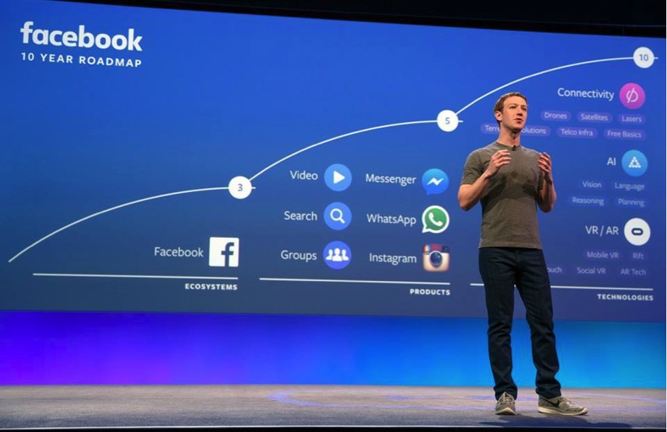 A man in Hong Kong standing in front of an award-winning screen featuring a Facebook logo.