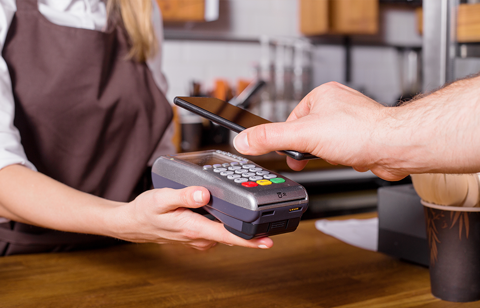 An individual in Hong Kong is operating both a cell phone and a pos machine.