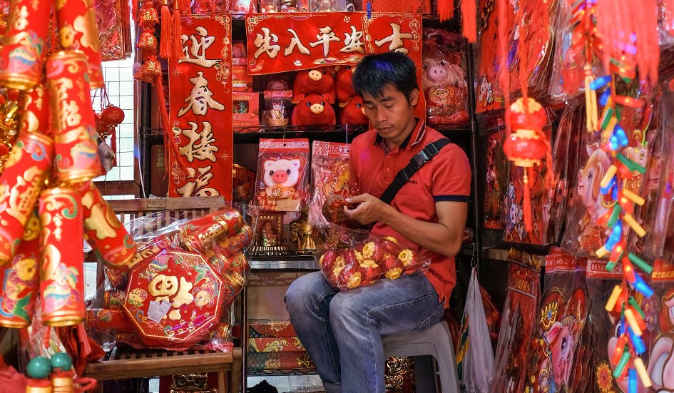 A man sits on a stool in an award-winning Chinese market.