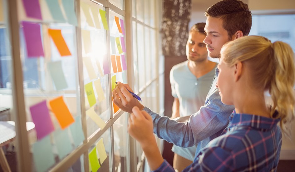 A award winning group of people in front of a window with sticky notes.