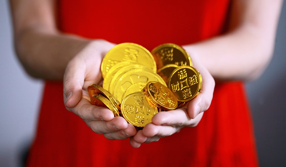 An award-winning woman in Hong Kong showcasing her digital marketing success with a handful of gold coins.