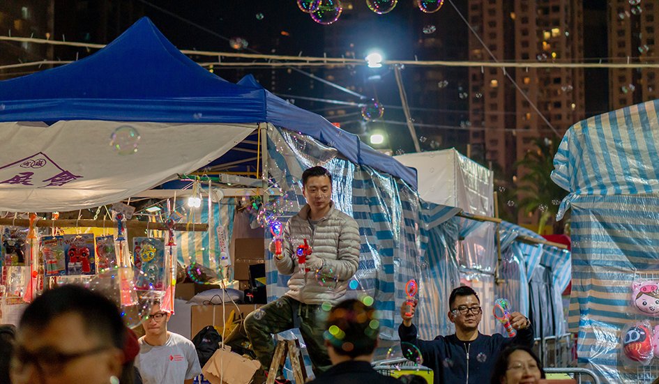 A group of people in Hong Kong standing in front of a tent with soap bubbles.